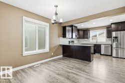 Kitchen with appliances with stainless steel finishes, a chandelier, decorative light fixtures, dark brown cabinetry, and backsplash - 