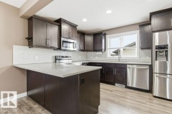 Kitchen with appliances with stainless steel finishes, dark brown cabinetry, a peninsula, light wood finished floors, and decorative backsplash - 