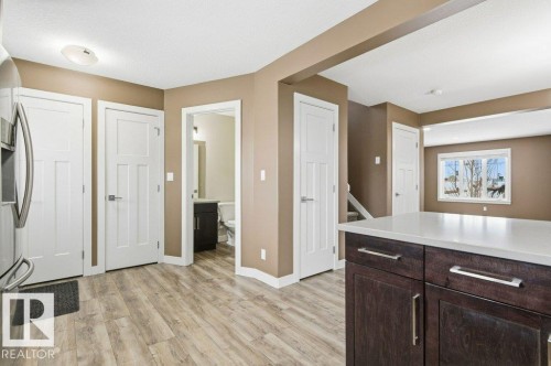 Kitchen featuring dark brown cabinetry, light wood-style flooring, and stainless steel fridge - 2 Wingate Way, Fort Saskatchewan, AB - Indoor Photo Showing Other Room