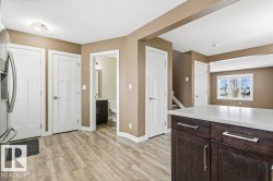 Kitchen featuring dark brown cabinetry, light wood-style flooring, and stainless steel fridge - 
