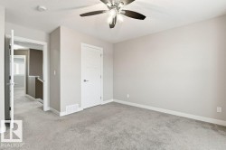 Unfurnished bedroom with light colored carpet, a ceiling fan, and a textured ceiling - 