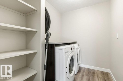 Laundry area featuring light wood-type flooring, washer and clothes dryer, and a textured ceiling - 2 Wingate Way, Fort Saskatchewan, AB - Indoor Photo Showing Laundry Room