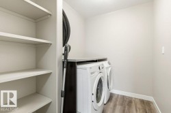 Laundry area featuring light wood-type flooring, washer and clothes dryer, and a textured ceiling - 