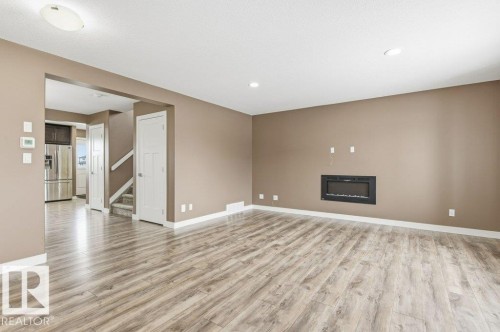 Unfurnished living room featuring stairs, a fireplace, light wood finished floors, and recessed lighting - 2 Wingate Way, Fort Saskatchewan, AB - Indoor With Fireplace