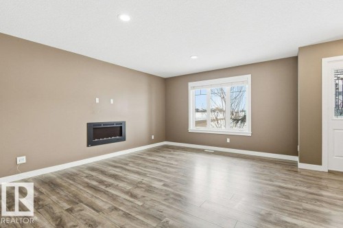 Unfurnished living room featuring a fireplace, light wood-style flooring, and recessed lighting - 2 Wingate Way, Fort Saskatchewan, AB - Indoor Photo Showing Living Room With Fireplace