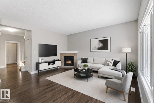Living room featuring a tile fireplace, dark wood-style flooring, a textured ceiling, and stairway - 3683 8 Street, Edmonton, AB - Indoor Photo Showing Living Room With Fireplace