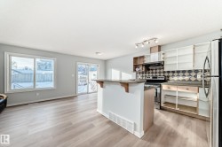 Kitchen with a kitchen bar, appliances with stainless steel finishes, backsplash, open shelves, and light wood finished floors - 