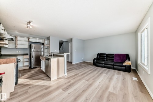 Kitchen with appliances with stainless steel finishes, white cabinetry, light wood finished floors, open floor plan, and open shelves - 7731 8 Avenue, Edmonton, AB - Indoor Photo Showing Kitchen With Stainless Steel Kitchen