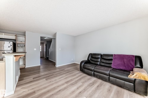 Living room featuring light wood-style floors and a textured ceiling - 7731 8 Avenue, Edmonton, AB - Indoor