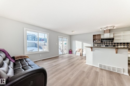 Living room with light wood-type flooring and baseboards - 7731 8 Avenue, Edmonton, AB - Indoor Photo Showing Living Room