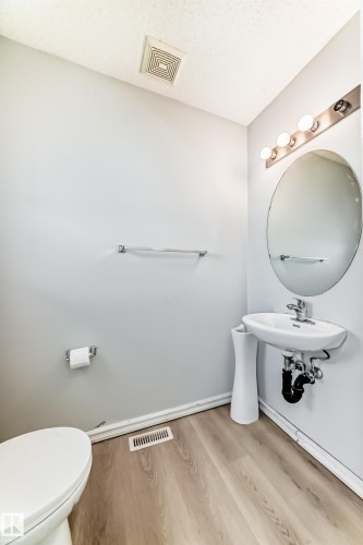 Half bath featuring light wood-type flooring and a textured ceiling - 7731 8 Avenue, Edmonton, AB - Indoor Photo Showing Bathroom