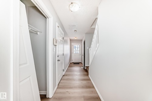 Corridor with stairway, light wood-style floors, and a textured ceiling - 7731 8 Avenue, Edmonton, AB - Indoor Photo Showing Other Room