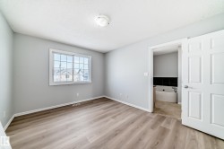 Unfurnished bedroom featuring light wood-type flooring, a textured ceiling, and connected bathroom - 