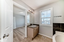 Bathroom with vanity, a textured ceiling, a tub to relax in, and light wood-style flooring - 