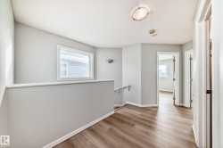 Hallway featuring an upstairs landing, light wood finished floors, and a textured ceiling - 