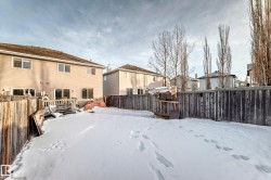 Snow covered rear of property with a fenced backyard, a residential view, and a wooden deck - 