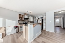 Kitchen with a breakfast bar, open shelves, light wood-style flooring, backsplash, and a textured ceiling - 