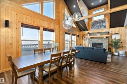 Dining area featuring wood walls, high vaulted ceiling, a fireplace, and dark wood-style flooring - 