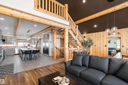 Living room featuring wooden walls, dark wood-type flooring, a chandelier, recessed lighting, and stairway - 