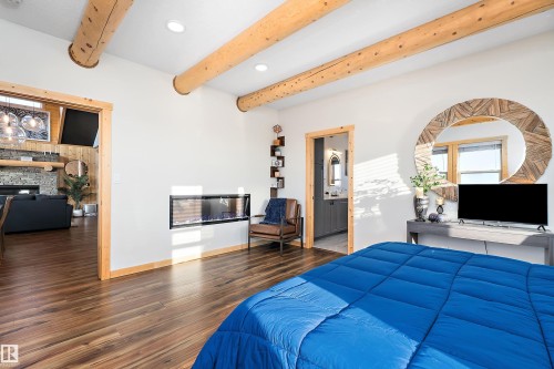Bedroom featuring recessed lighting, wood finished floors, ensuite bathroom, a stone fireplace, and beamed ceiling - 19003 Twp Rd 522, Rural Beaver County, AB - Indoor