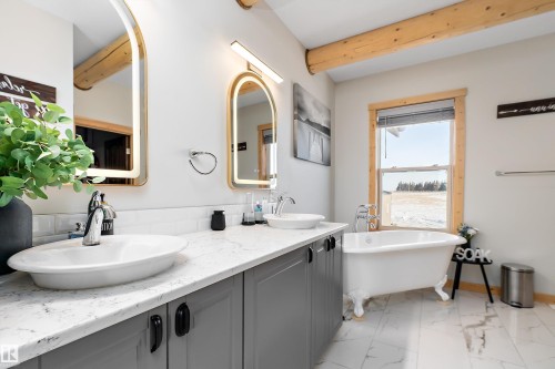 Full bathroom featuring double vanity, a freestanding tub, light marble finish flooring, and beamed ceiling - 19003 Twp Rd 522, Rural Beaver County, AB - Indoor Photo Showing Bathroom