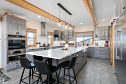Kitchen with gray cabinets, decorative light fixtures, a barn door, beam ceiling, and tasteful backsplash - 