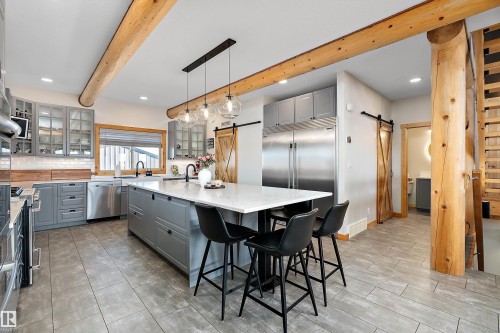 Kitchen featuring gray cabinets, a barn door, glass insert cabinets, hanging light fixtures, and beamed ceiling - 19003 Twp Rd 522, Rural Beaver County, AB - Indoor Photo Showing Kitchen With Upgraded Kitchen