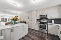 Kitchen featuring appliances with stainless steel finishes, dark wood finished floors, backsplash, track lighting, and a textured ceiling - 