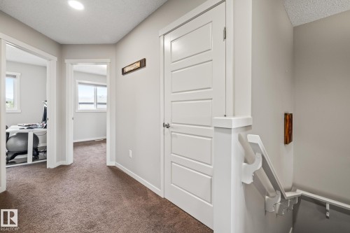 Hall with dark carpet, an office area, and a textured ceiling - 20110 27 Avenue, Edmonton, AB - Indoor Photo Showing Other Room
