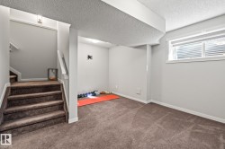 Below grade area featuring dark colored carpet, a textured ceiling, and stairs - 