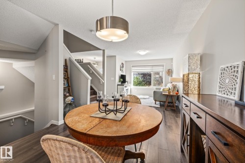 Dining space featuring dark wood finished floors, a textured ceiling, and stairway - 20110 27 Avenue, Edmonton, AB - Indoor Photo Showing Dining Room