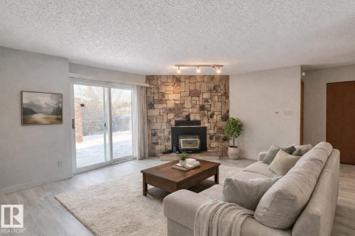 Living room featuring wood finished floors, a textured ceiling, and a wood stove - 2112 104B Street, Edmonton, AB - Indoor Photo Showing Living Room With Fireplace