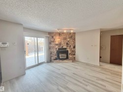 Unfurnished living room featuring a wood stove, a textured ceiling, and light wood-style flooring - 