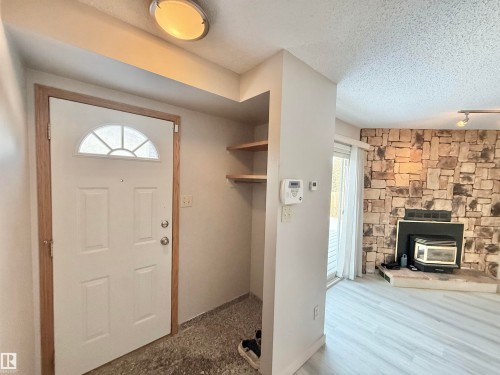 Foyer featuring a wood stove, a textured ceiling, and track lighting - 2112 104B Street, Edmonton, AB - Indoor With Fireplace