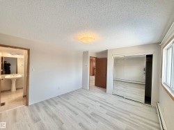 Unfurnished bedroom with baseboard heating, a closet, light wood finished floors, and a textured ceiling - 