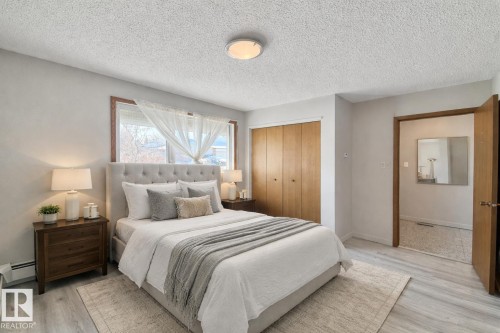 Bedroom with a textured ceiling, a closet, wood finished floors, and a baseboard heating unit - 2112 104B Street, Edmonton, AB - Indoor Photo Showing Bedroom