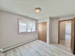 Unfurnished bedroom featuring baseboard heating, a textured ceiling, a closet, and wood finished floors - 