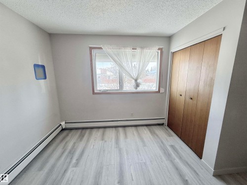 Unfurnished bedroom featuring a baseboard heating unit, light wood-style flooring, a textured ceiling, and a closet - 2112 104B Street, Edmonton, AB - Indoor Photo Showing Other Room