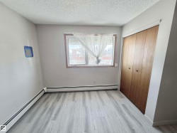 Unfurnished bedroom featuring a baseboard heating unit, light wood-style flooring, a textured ceiling, and a closet - 