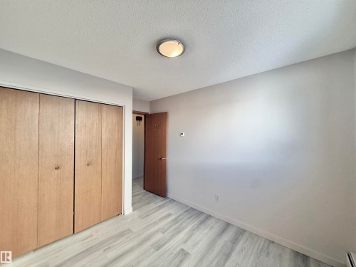 Unfurnished bedroom with a textured ceiling, a closet, and light wood-style flooring - 2112 104B Street, Edmonton, AB - Indoor Photo Showing Other Room