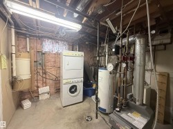 Unfinished basement with water heater, estacked washer and dryer, and a heating unit - 