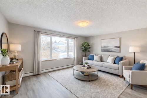 Living room with a textured ceiling, light wood-style floors, and baseboard heating - 2112 104B Street, Edmonton, AB - Indoor Photo Showing Living Room