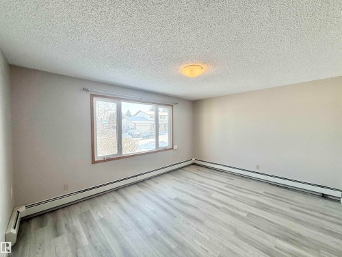 Spare room featuring baseboard heating, a textured ceiling, a baseboard heating unit, and light wood-style flooring - 2112 104B Street, Edmonton, AB - Indoor Photo Showing Other Room