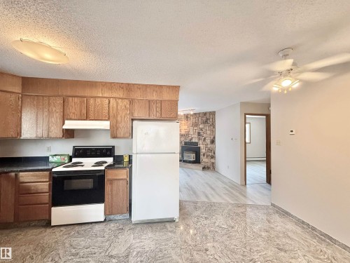 Kitchen featuring electric stove, freestanding refrigerator, dark countertops, a textured ceiling, and a ceiling fan - 2112 104B Street, Edmonton, AB - Indoor Photo Showing Kitchen