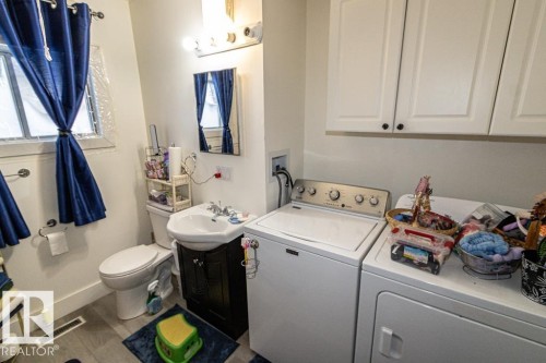 Bathroom with vanity, independent washer and dryer, and wood finished floors - 4922 47 Ave, St. Paul Town, AB - Indoor