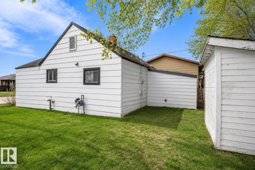 White siding exterior featuring a gable roofline, black-framed windows, and a detached shed - 4922 47 Ave, St. Paul Town, AB - Outdoor With Exterior