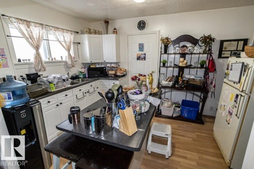 Kitchen featuring dark countertops, freestanding refrigerator, white cabinets, a textured ceiling, and light wood-style floors - 4922 47 Ave, St. Paul Town, AB - Indoor
