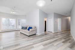 Living area with ceiling fan, light wood-style flooring, and a textured ceiling - 