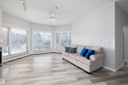 Living area featuring light wood-style flooring, plenty of natural light, a ceiling fan, a textured ceiling, and a baseboard heating unit - 