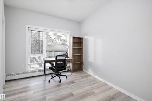 Second bedroom featuring light wood-type flooring, baseboard heating, and a textured ceiling - 205 10809 Saskatchewan Drive, Edmonton, AB - Indoor Photo Showing Office